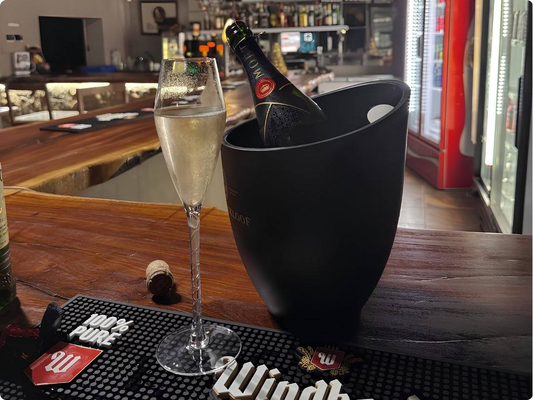 A glass of champagne beside a chilled bottle in an ice bucket at the Omateko bar