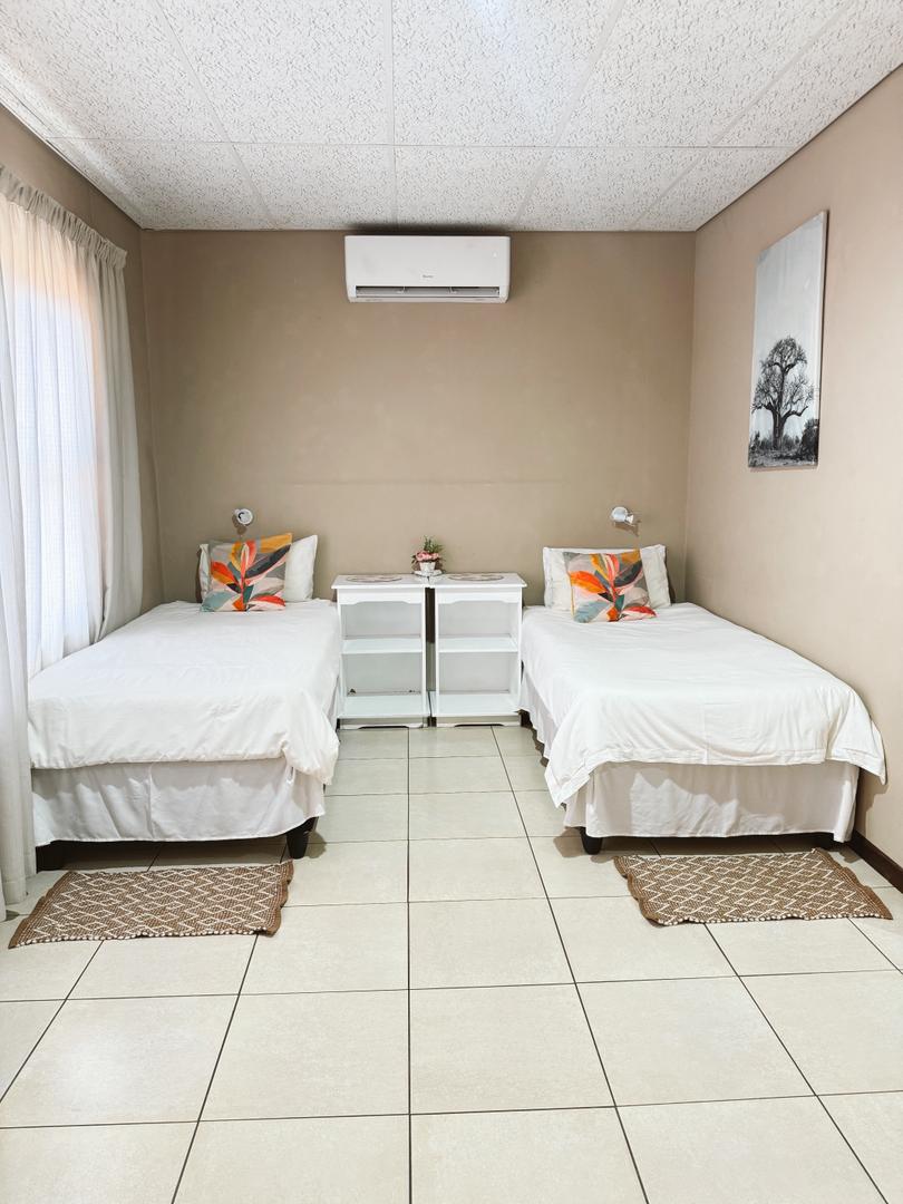 Single Room at Omateko Lodge with twin beds, air conditioning and Kalahari-inspired decor